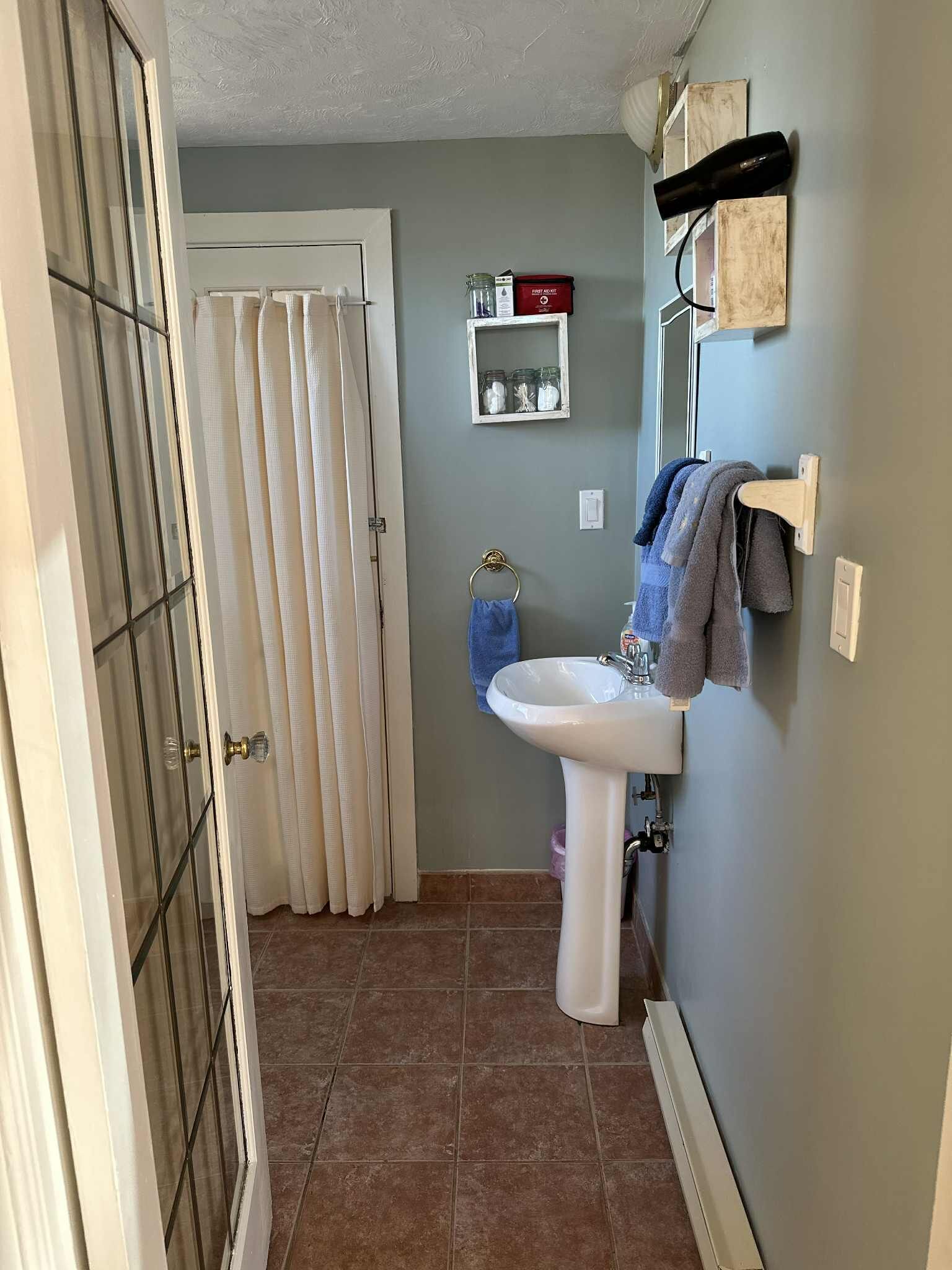Une salle de bain avec un lavabo sur colonne, une douche avec une porte en verre et un porte-serviettes avec des serviettes.
