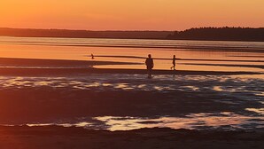 Een strandscène met rustig water en een zonsondergang.