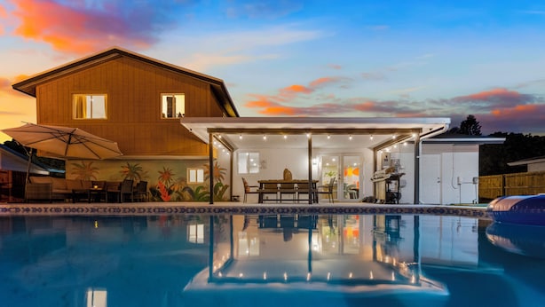 Ein modernes Haus mit Swimmingpool, Terrasse und Essbereich im Freien.
