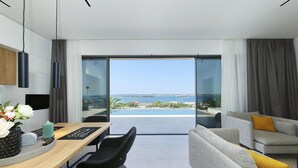 A modern living room with a sofa, a dining table with chairs, and a view of the sea through large glass doors. - Awesome home in Tkon with private swimming pool, can be inside or outside (Tkon)