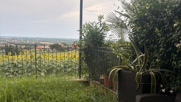 Ein Balkon mit Glastisch, Korbmöbeln und Blick auf eine Stadtlandschaft.