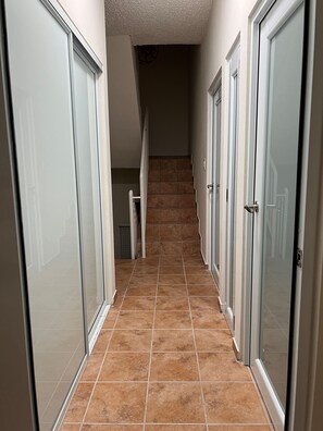 Un couloir au sol carrelé, avec des portes blanches de chaque côté.