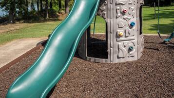 Un parque infantil con un tobogán verde y estructuras para escalar.