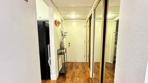 Un couloir doté d’un plancher en bois, de murs blancs et d’un réfrigérateur noir.