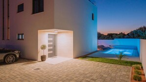 A modern house with a swimming pool, a car parked in the driveway, and a well-maintained garden. - Amazing home in Mandre (Mandre)