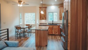 Una cocina moderna con armarios de madera, una isla central y una zona de comedor con sillas.