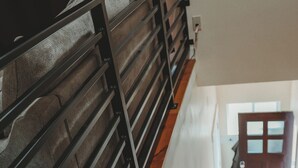 Una escalera de madera con barandilla de metal que conduce a una puerta con panel de vidrio.