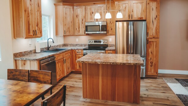 Una cocina con armarios de madera, un refrigerador de acero inoxidable, un microondas y una encimera de granito.