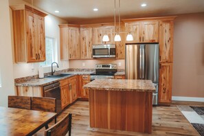 A kitchen with wooden cabinets, a stainless steel refrigerator, a microwave, and a granite countertop. - Treetop Views 2 bedroom 2 bath w A/C (Island Park)