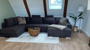 A modern loft-style living room with a sectional sofa, a wooden coffee table, and a skylight.