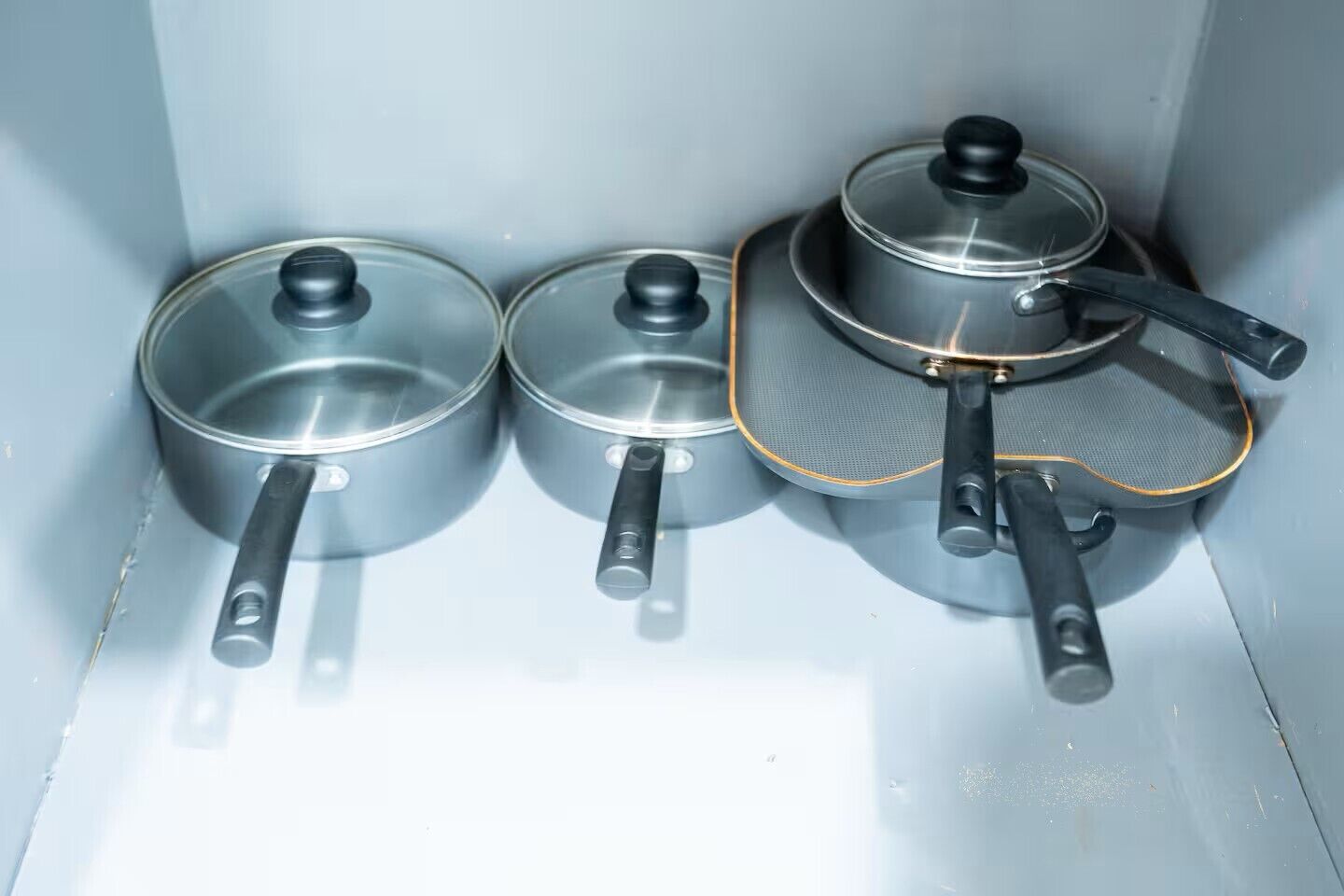 Three kitchen utensils: a pan, a frying pan, and a grater.