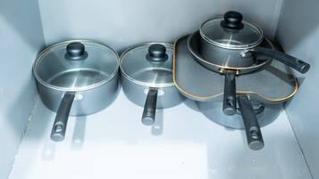 Three kitchen utensils: a pan, a frying pan, and a grater.