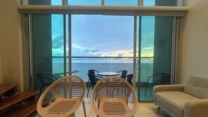 Ein Balkon mit zwei Stühlen und einem Tisch, mit Blick auf ein Gewässer.