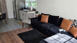 Un salon moderne avec un canapé d’angle noir, une table basse en bois et un ventilateur de plafond.
