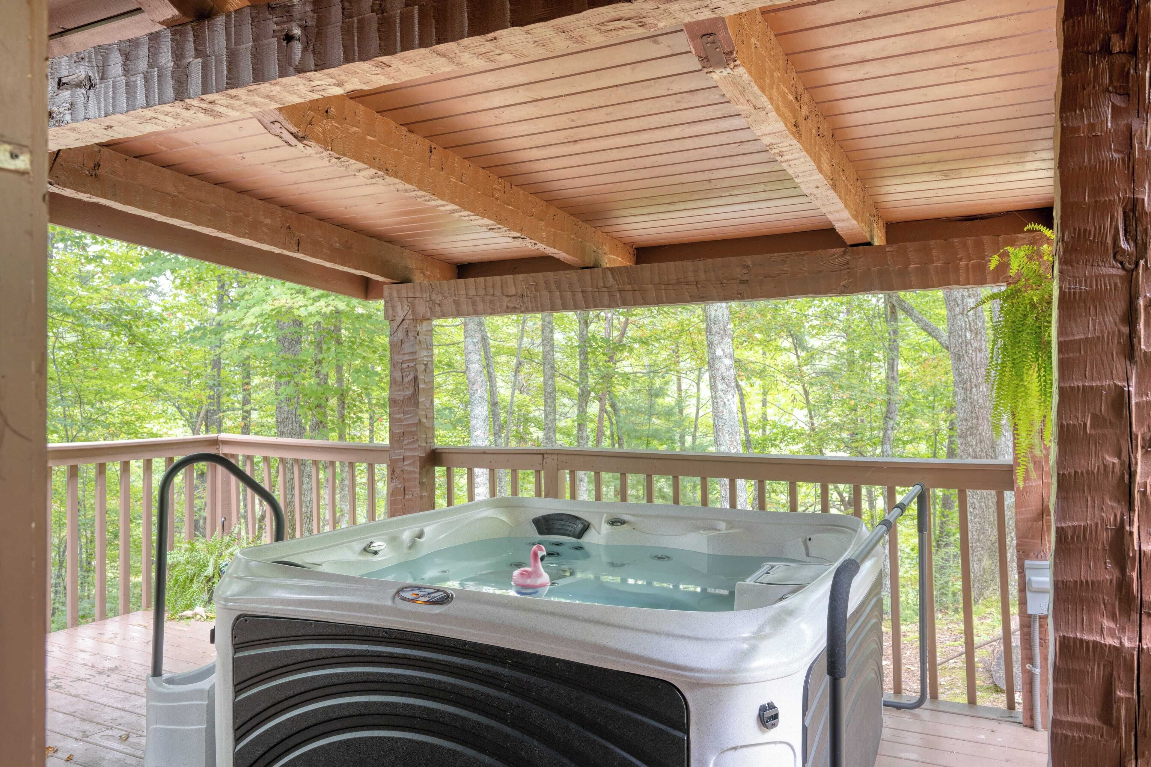 A hot tub on a wooden deck with a view of a forest.