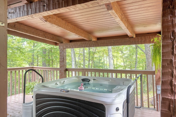 Ein Whirlpool auf einer Holzterrasse mit Blick auf einen Wald.