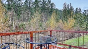 A wooden deck with a glass table and chairs, surrounded by a forest. - Granite Peak. Near Mt-Rushmore National Memorial (Keystone)