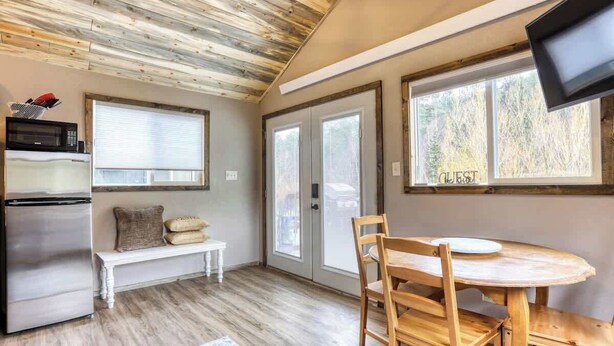 A kitchen with a wooden ceiling, a refrigerator, a microwave, a bench, and a dining table with chairs. - Granite Peak. Near Mt-Rushmore National Memorial (Keystone)