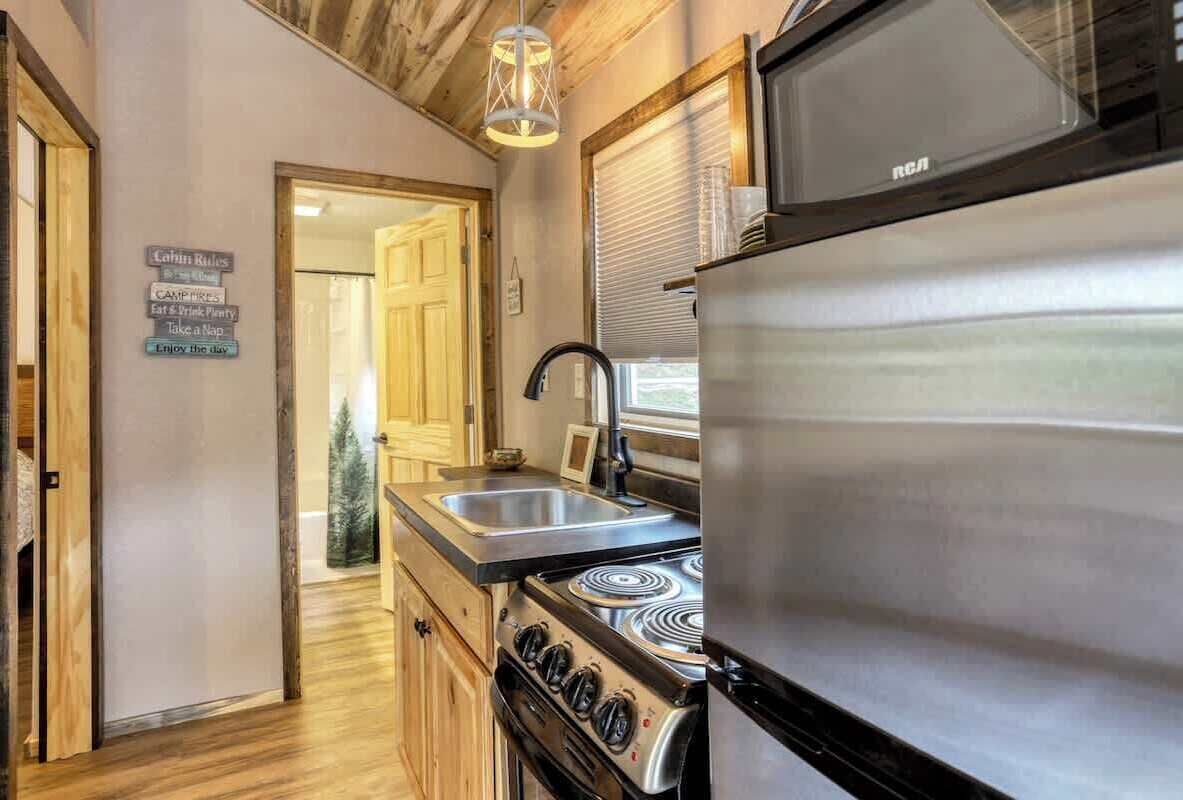 Una cocina compacta con refrigerador, estufa, pileta y alacenas de madera.