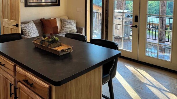 A spacious kitchen with a central island, wooden cabinets, and a large window providing a view of the outdoors. - In the center of all the Black Hills has to offer, The Elkhorn Cabin with a Hot Tub (Keystone)