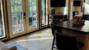 A spacious room with a large dining table, two chairs, a TV mounted on the wall, and a ceiling fan. - In the center of all the Black Hills has to offer, The Elkhorn Cabin with a Hot Tub (Keystone)
