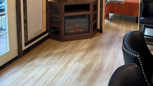 A cozy room with a flat-screen TV, a fireplace, and a bed with a window view. - In the center of all the Black Hills has to offer, The Elkhorn Cabin with a Hot Tub (Keystone)