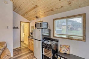 A compact kitchen with a stove, microwave, and refrigerator.