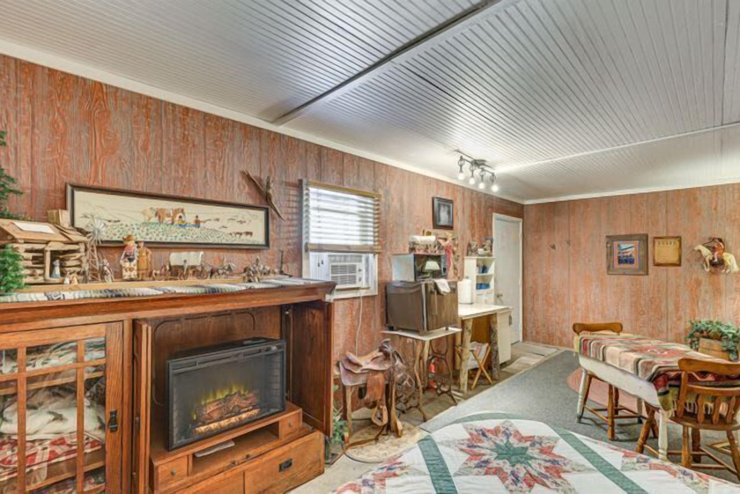 A room with a fireplace, wooden furniture, a television, and a framed picture on the wall.