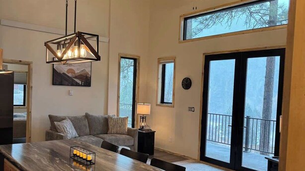 A spacious kitchen with a large island, wooden ceiling, and large windows.