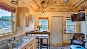 A kitchen with wooden cabinets, a granite countertop, and a bar area with stools. - The Little Pine, 3 Miles to Mt. Rushmore National (Keystone)