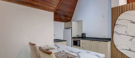 Una cocina moderna con encimera de mármol, techo de madera y un comedor con mesa y sillas.