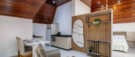 A modern kitchen with a marble backsplash, wooden ceiling, and a dining area with a marble table and cushioned chairs.