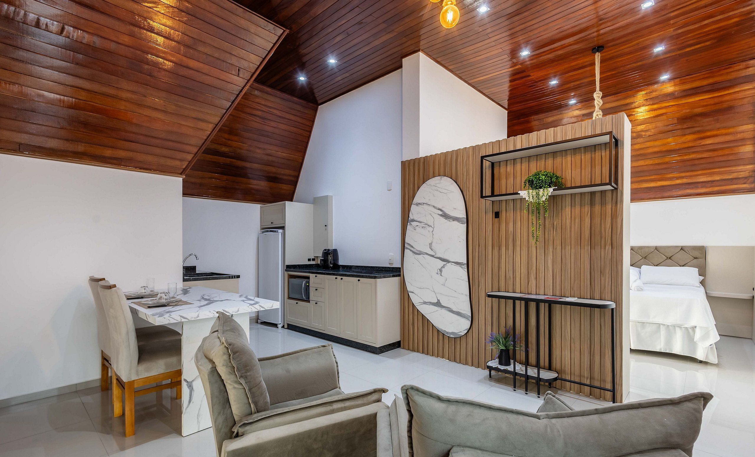 A modern kitchen with a marble backsplash, wooden ceiling, and a dining area with a marble table and cushioned chairs.