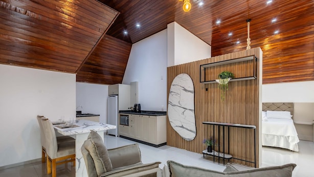 Cocina moderna con salpicadero de mármol, techo de madera y comedor con mesa de mármol y sillas acolchadas.