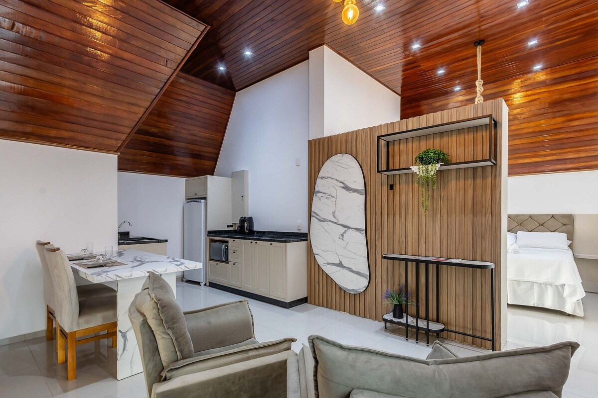 Cocina moderna con salpicadero de mármol, techo de madera y comedor con mesa de mármol y sillas acolchadas.