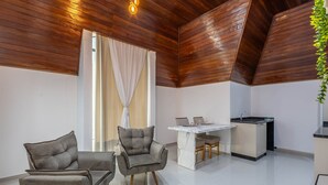 Una cocina moderna con encimera de mármol, techo de madera y zona de comedor con dos sofás grises y una mesa.