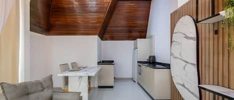A modern kitchen with a marble countertop, wooden ceiling, and a dining area with a sofa and table.