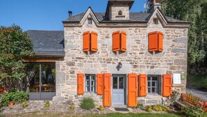 A stone building with orange shutters, a door, and a small tower.