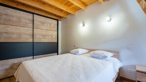 A bedroom with a wooden ceiling, a bed with white bedding, and a nightstand. - Lozeret vacation rentals (CUBIERES)