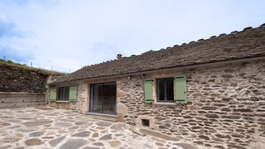 A stone building with a tiled patio, green shutters, and a small window. - Lozeret vacation rentals (CUBIERES)