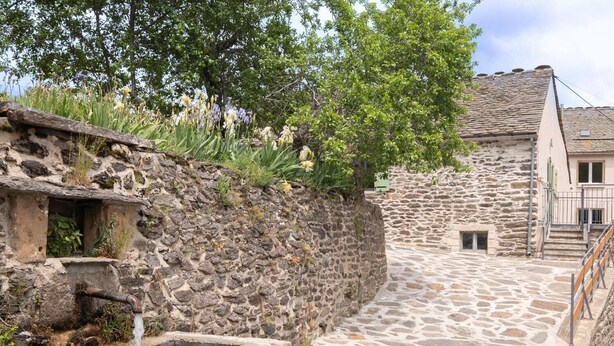 A stone pathway leading to a rustic stone building with a small water feature and lush greenery. - Lozeret vacation rentals (CUBIERES)
