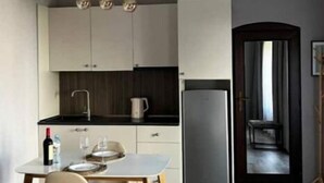 Eine moderne Küche mit Esstisch, Stühlen, einem Kühlschrank und Pendelleuchten.