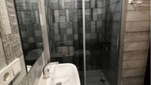 Ein Badezimmer mit Duschkabine, Waschbecken und Fliesen.
