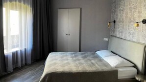 Ein modernes Hotelzimmer mit einem großen Bett, einem Kleiderschrank und einer Wandleuchte.