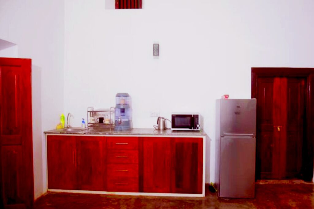Una cocina pequeña con refrigerador, microondas y cafetera sobre la encimera.