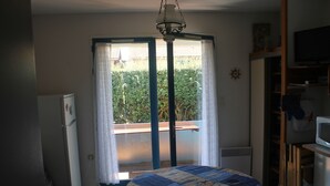 Una cocina compacta con una mesa redonda, un refrigerador y una ventana con cortinas.