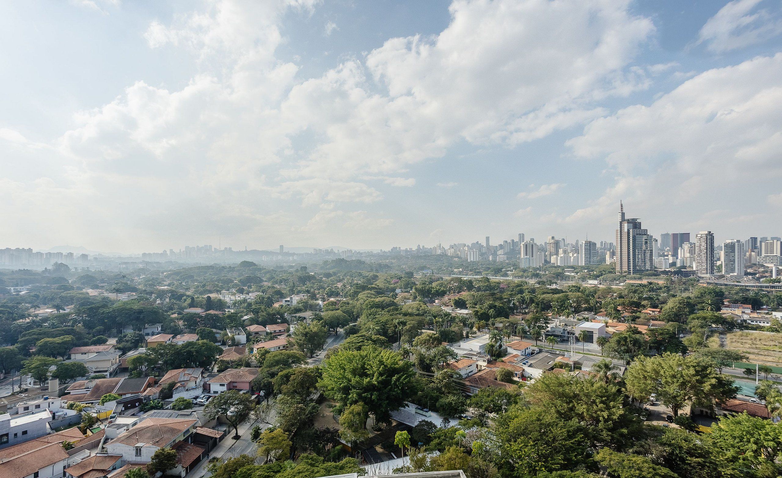 Un paisaje urbano con edificios residenciales y comerciales, un rascacielos destacado y un cielo despejado.