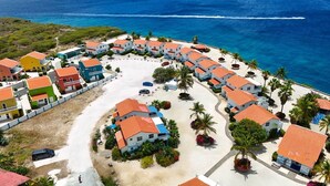 A coastal resort with multiple buildings, a sandy beach, and a clear view of the ocean.