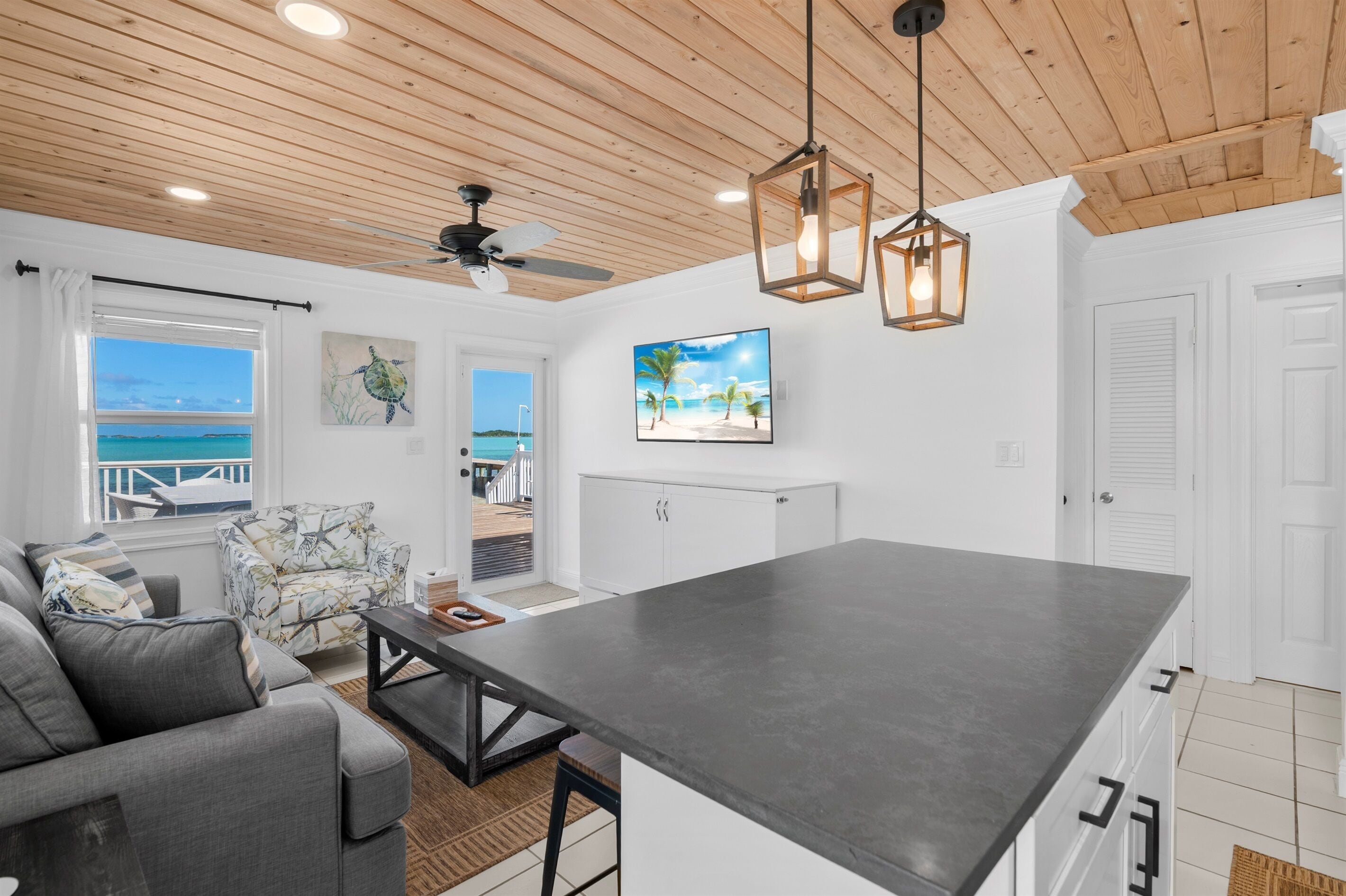A modern kitchen with a large island, white cabinetry, and a view of the ocean.
