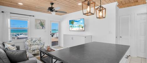 A modern kitchen with a large island, white cabinetry, and a view of the ocean.
